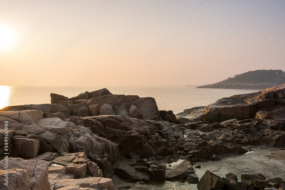 Sunrise over the sea and stone at the seaside of Mount Putuo in the morning, an island southeast of Shanghai in Zhoushan, Zhejiang, China, the bodhimaṇḍa of the bodhisattva Guanyin.