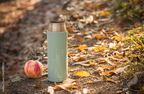 open candleand ripe apple on the background of a road strewn with autumn leaves