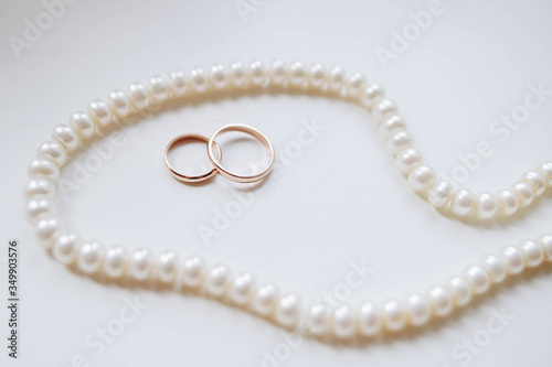 Wedding gold rings on a white background surrounded by pearls