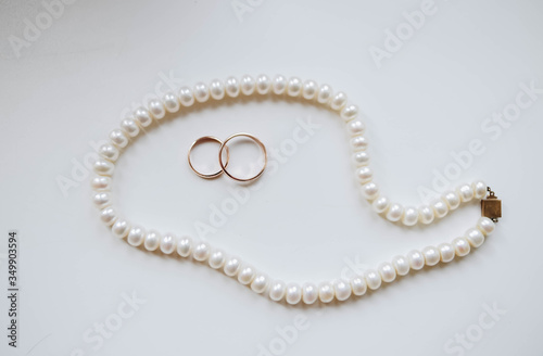 Wedding gold rings on a white background surrounded by pearls