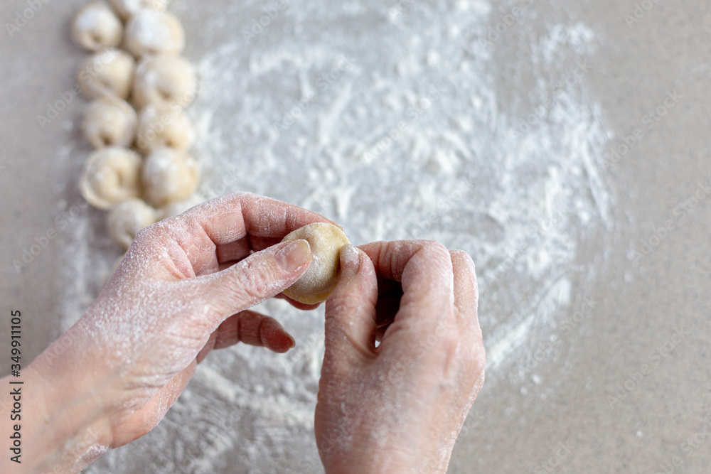 Woman sculpts homemade dumplings bear ears in the kitchen. Modeling dumplings closeup. Female hands sculpt dumplings.