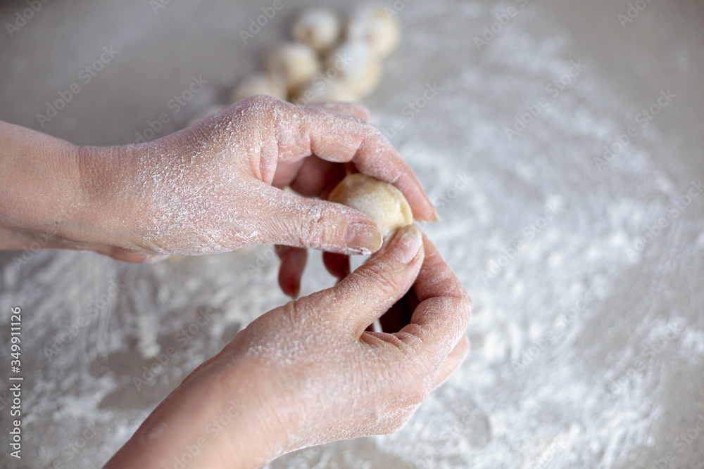 Woman sculpts homemade dumplings bear ears in the kitchen. Modeling dumplings closeup. Female hands sculpt dumplings.