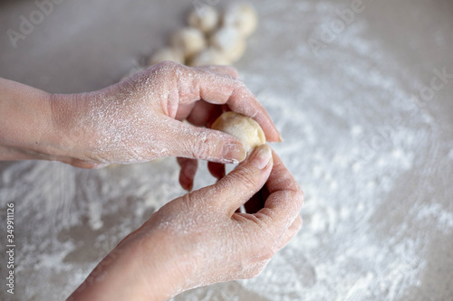 Woman sculpts homemade dumplings bear ears in the kitchen.  Modeling dumplings closeup.  Female hands sculpt dumplings.