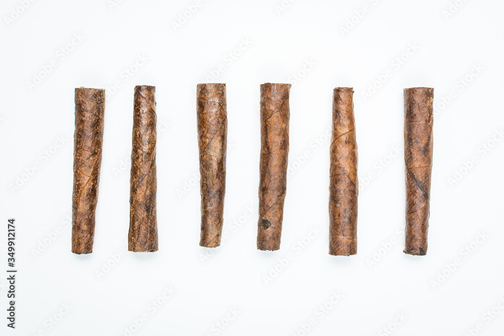 Small cigars lie in row on white background. Small cigars lie in row on white background.