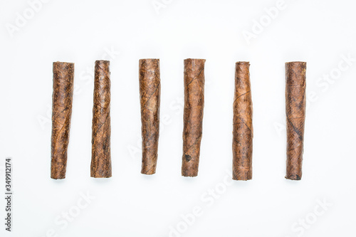 Small cigars lie in row on white background.
