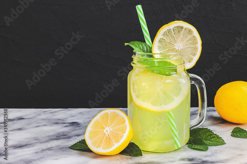 Lemon lemonade in mason jar glass ofwith lemons and straw on tab