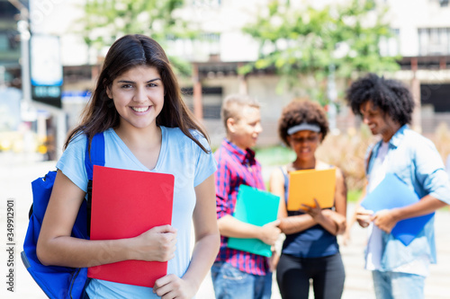 Beautiful hispanic female student with group of multi ethnic young adults