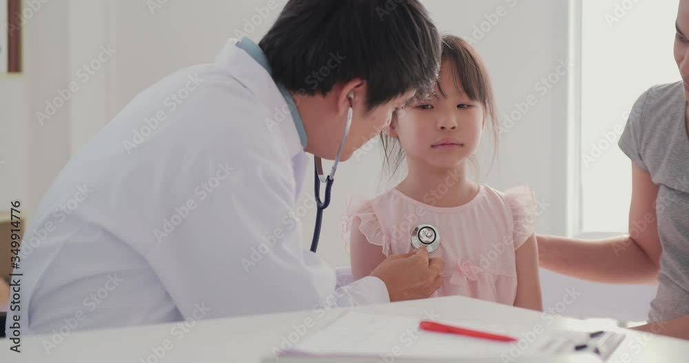 Little asian girl patient was check by male doctor and mom looking to her, small preschool child with parent visiting pediatrician doing medical checkup laughing having fun at medical consultation.