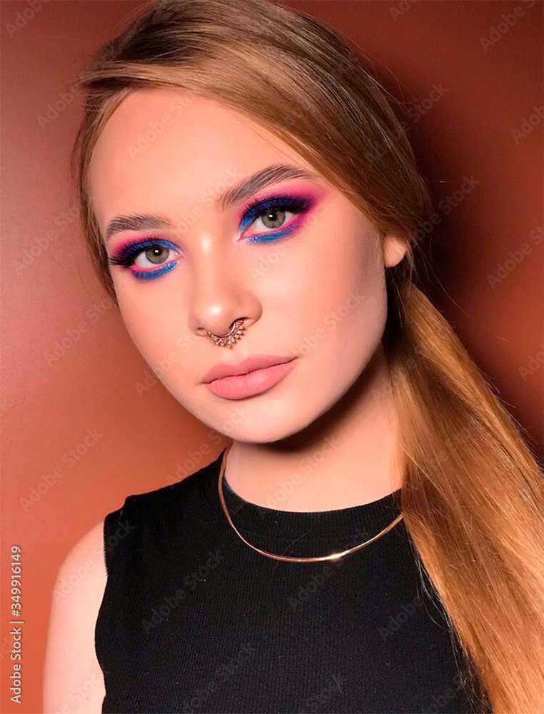 Fototapeta premium Portrait of a beautiful girl. Natural fair hair. Bright blue makeup. Puffy lips. Northern appearance.