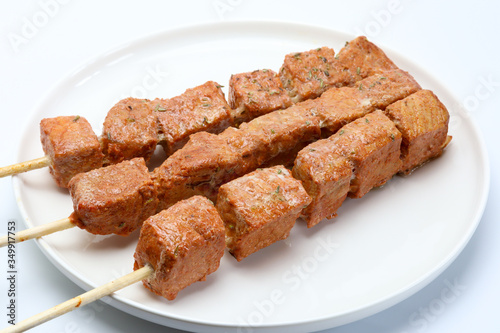Pincho o brocheta de carne asada en un plato con fondo blanco
