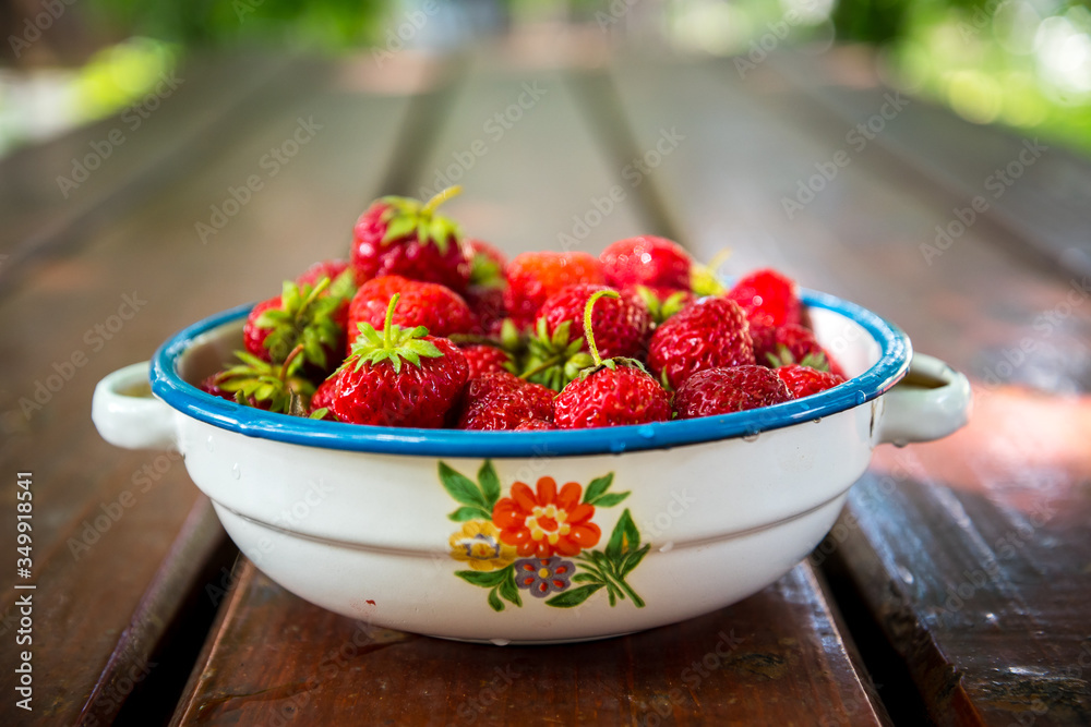 Plate with group of ripe, delicious strawberry on a brown wooden table. Selective focus Plate with group of ripe, delicious strawberry on a brown wooden table. Selective focus