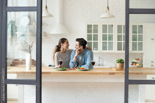 Bild auf Leinwand Happy Caucasian millennial husband and wife relax drink wine in modern new home