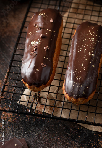 close-up of profiteroles topped with chocolate glaze and golden powder (kandurin). gourmet dessert. dark background. vertical image. photo