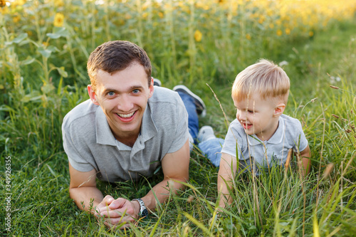 Father and son having fun on the grass. Little boy and his dad lying and laughing. Summer outdoors lifestyle, family leisure, parenthood © bearmoney