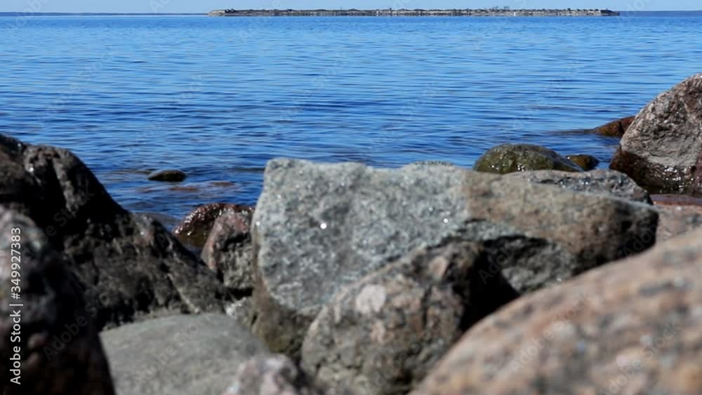 Landscape. View of blue sea slowly flows around the coastal stones in the foreground. On the horizon is a fort. Tourism concept Landscape. View of blue sea slowly flows around the coastal stones in the foreground. On the horizon is a fort. Tourism concept