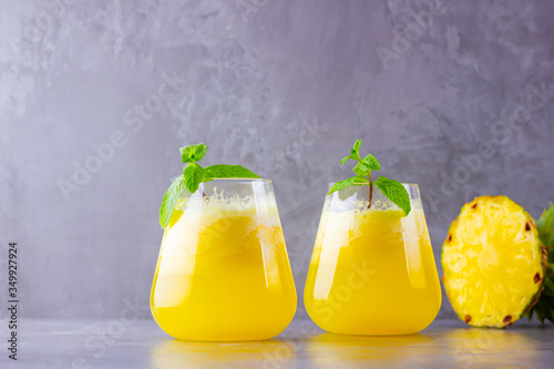 Pineapple juice on a gray background. Juice for detox in the glass. Pineapple smoothie with fresh pineapple. Healthy summer drink with mint