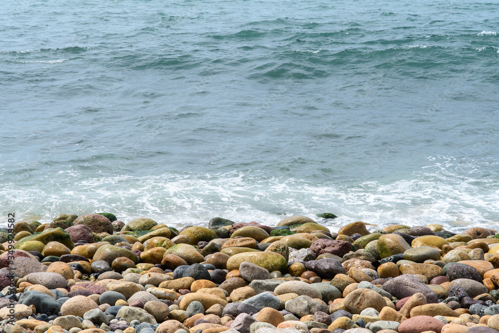A sea wave rolls onto the coastal boulders. Background. Abstract. A sea wave rolls onto the coastal boulders. Background. Abstract.
