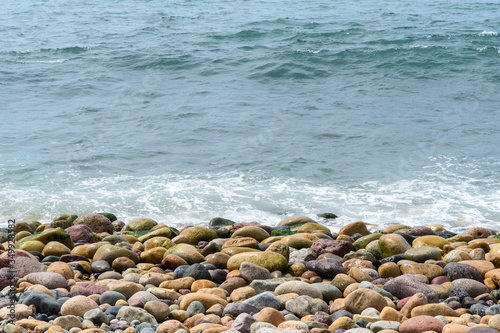 A sea wave rolls onto the coastal boulders. Background. Abstract.