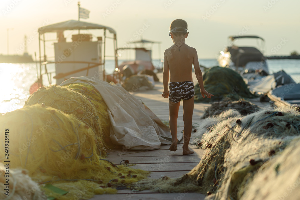 boy on pier through  fishing nets and boats