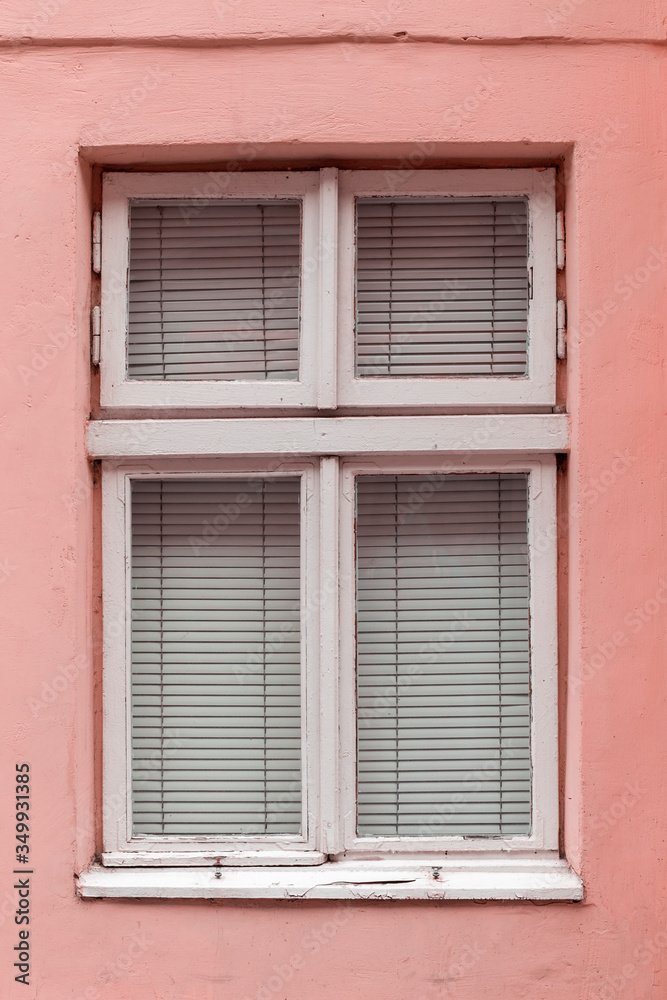 Old vintage window in a white wooden frame on a pink wall.