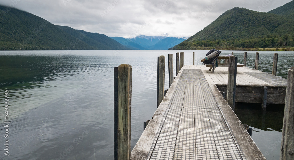 Jetty on the bank of lake surrounded with mountains, shot at Nelson Lakes National Park, New Zealand