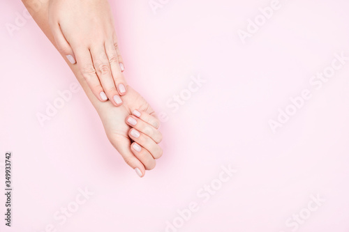 Beautiful women s hands with a neat delicate manicure on a pink background