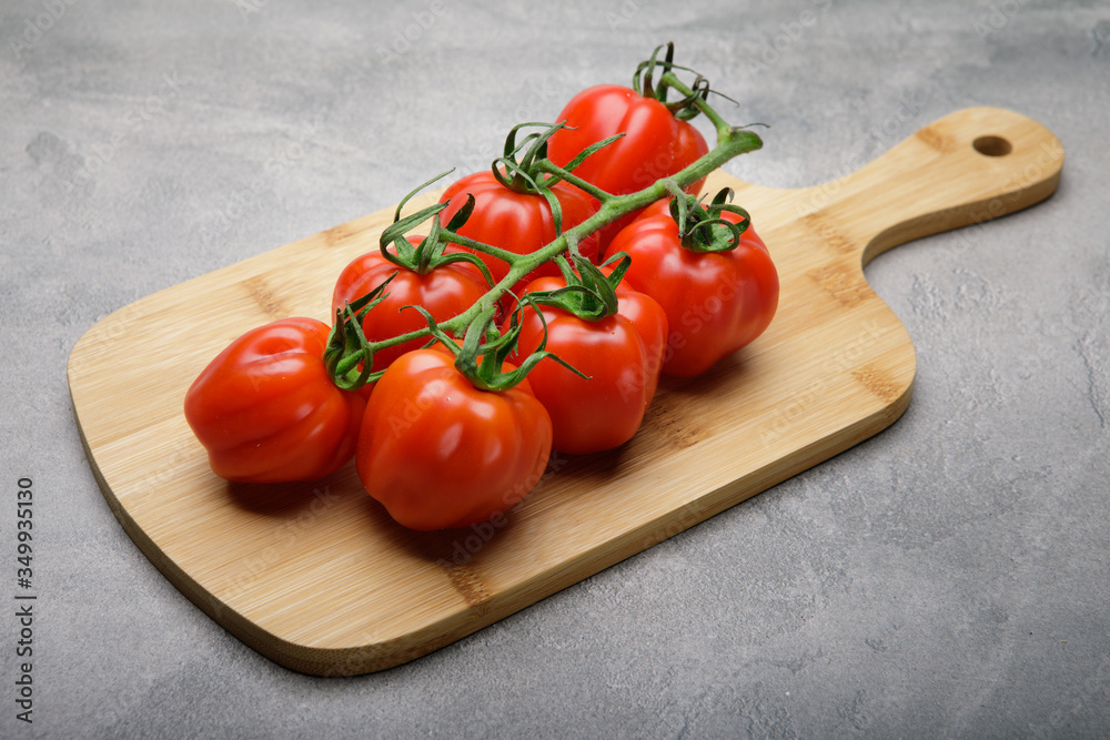 Red tomato on a cutting board on concrete background. Copy space. Fresh tomato wased for cooking Red tomato on a cutting board on concrete background. Copy space. Fresh tomato wased for cooking