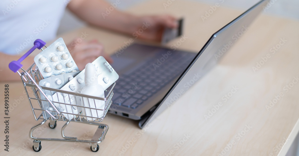 Online pharmacy concept. A woman holds a bank card in her hands and buys pills online. A girl makes an online purchase of pharmaceuticals with home delivery on a laptop. Online pharmacy concept. A woman holds a bank card in her hands and buys pills online. A girl makes an online purchase of pharmaceuticals with home delivery on a laptop.