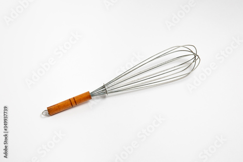 Clean new steel whisk isolated on white background. Cooking egg beater mixer whisker with wooden handle. High-resolution photo.
