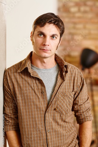 Portrait of thoughtful man leaning against wall, looking away.