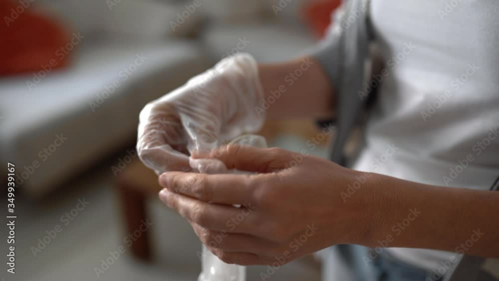 Woman putting on gloves at home during Covid-19 quarantine. Woman putting on gloves at home during Covid-19 quarantine.