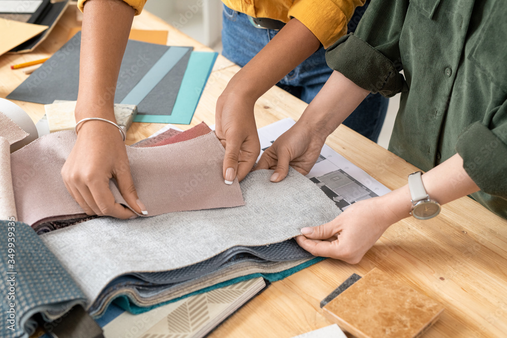 Fototapeta premium Two young contemporary female interior designers choosing furniture textile