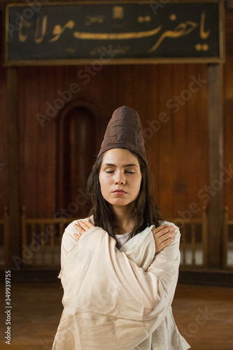 Portrait for a Sufi whirling woman dancer wearing white dress (Turkish/Semazen) performing art of Sama or physically active meditation of Sufism, and during spiritual dancing performance at Egypt