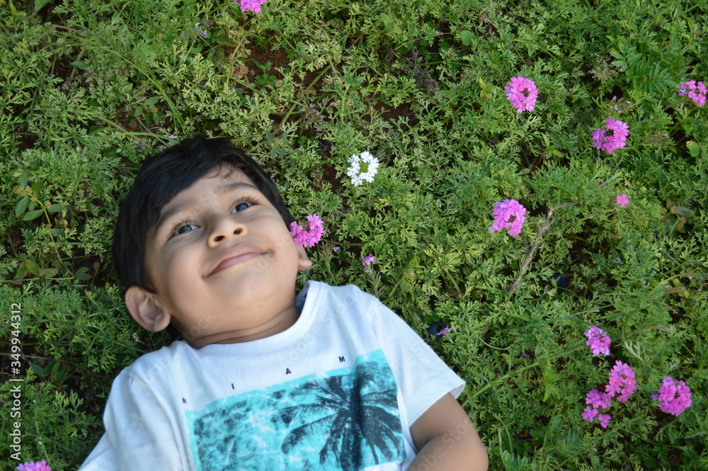 Cute baby boy kid sleeping lying in flowers green grass happy smiling Cute baby boy kid sleeping lying in flowers green grass happy smiling