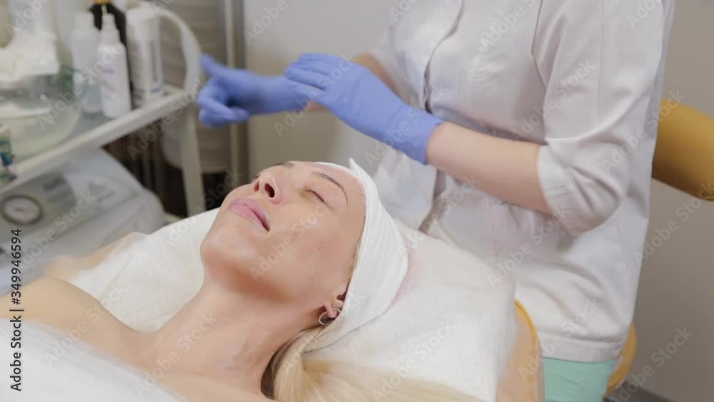 Professional beautician washes the mask off the face of a woman. Professional beautician washes the mask off the face of a woman.