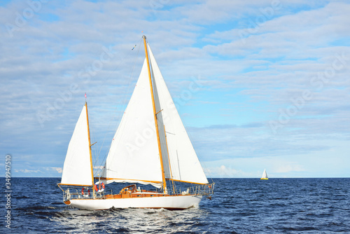 Old expensive vintage wooden sailboat (yawl) close-up, sailing in an open sea. Stunning cloudscape. Coast of Maine, US
