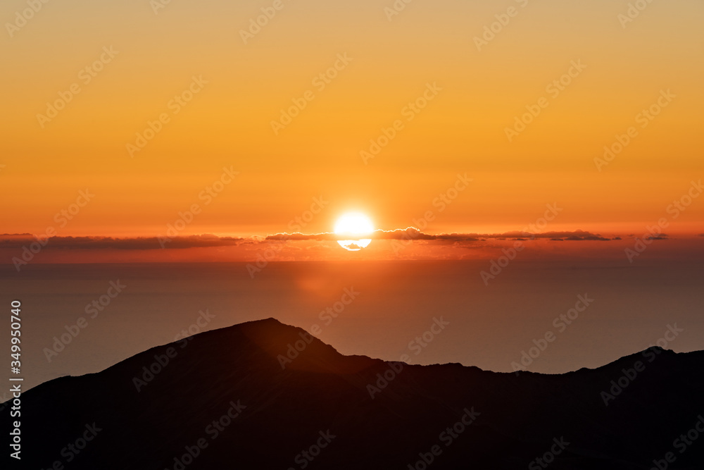 Sunrise over Haleakala Volcano on Maui in Hawaii with silhouetted mountain in the foreground