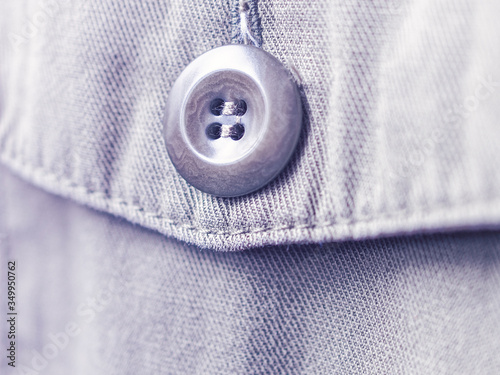 The button is sewn on the flap of a khaki jeans jacket pocket. The fabric texture is clearly visible.