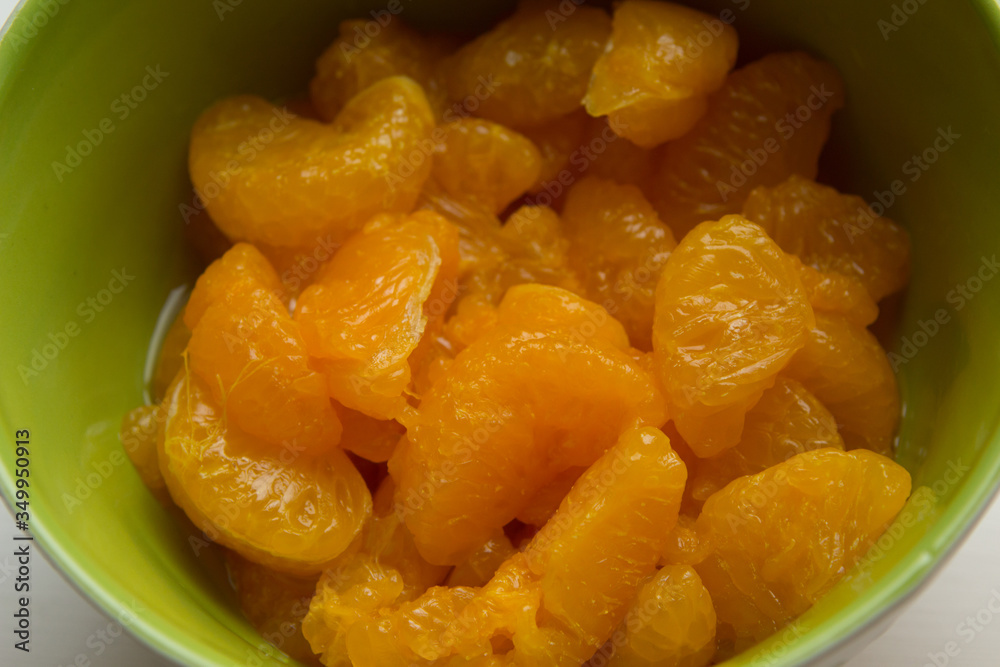 Canned tangerines in sweet sugar syrup are in a green deep bowl Canned tangerines in sweet sugar syrup are in a green deep bowl