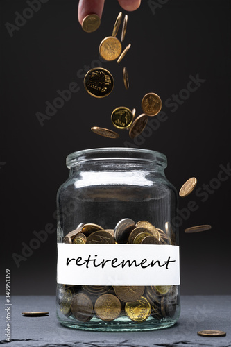 Coins in a jar with retirement text on a white label. Caucasian man throwing money from above. Savings abstract concept. Copy space. Vertical orientation.