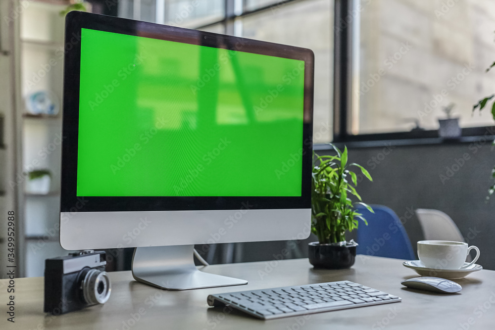 Computer desktop with mock-up green screen white background in office and Lovely plant in black pot Computer desktop with mock-up green screen white background in office and Lovely plant in black pot
