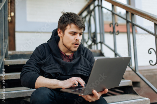 Young male working on his laptop computer in the city center. An independent person typing something in his document. chatting with friends over the internet, webcam