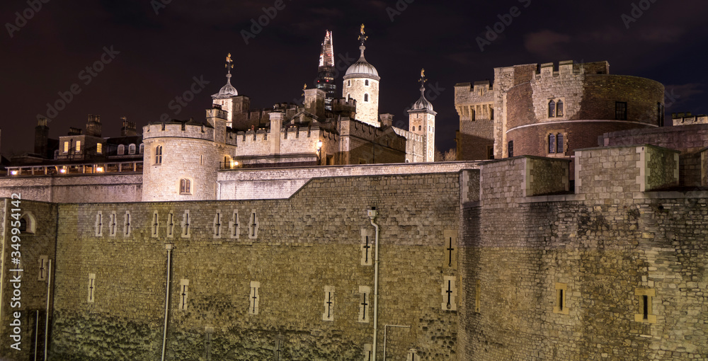 The Tower of London at night with skyscrapers illuminated in background