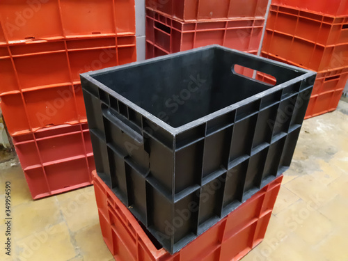 The big black plastic crate is surrounded by red plastic crates