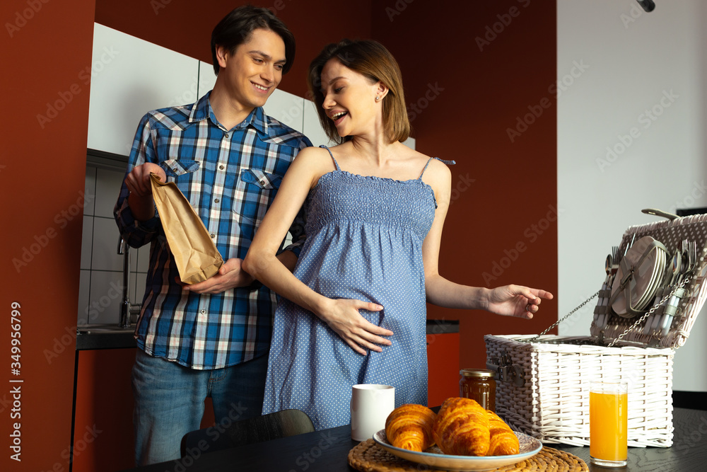 Merry spouses preparing for picnic while expecting baby