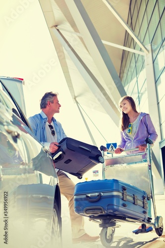 Portrait of mature man putting luggage on car trunk with lens flare  © moodboard