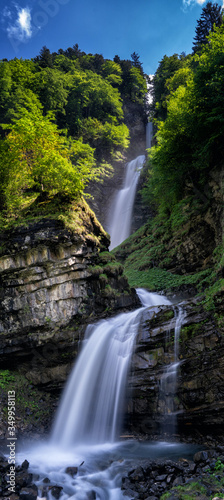 vertical panorama of the idyllic Diesbach creek waterfall in the Swiss Alps near Braunwald and Glarus in the spring