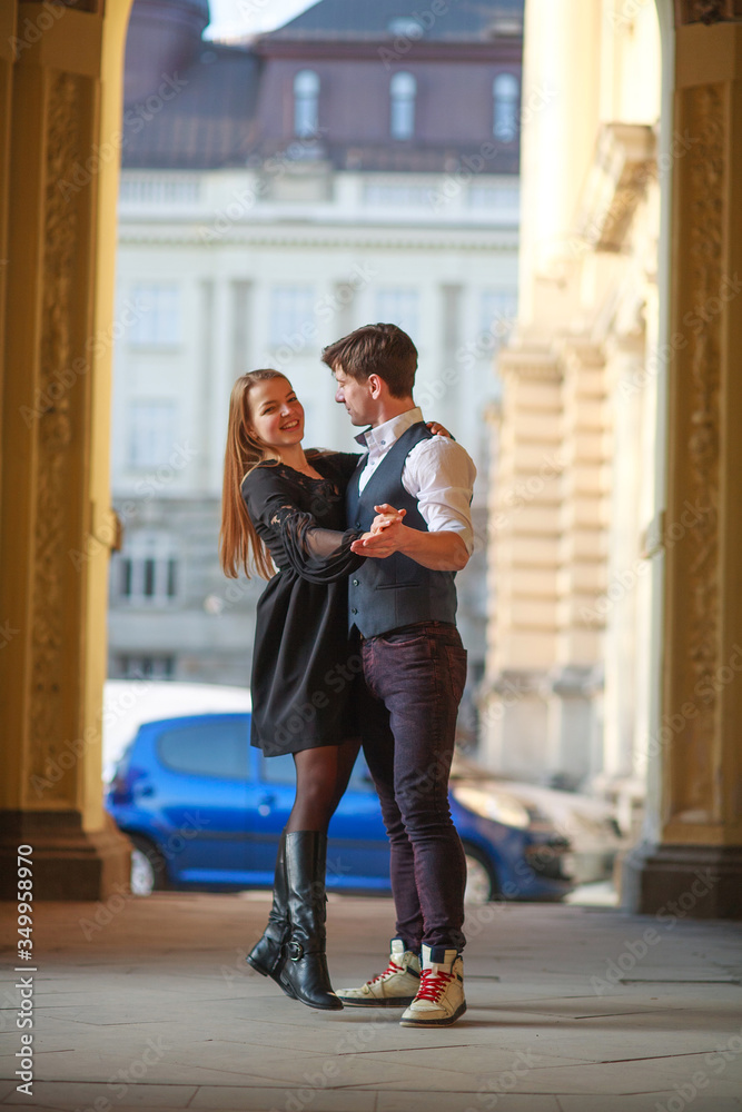 Young couple guy and girl dancing together on street of a European town
