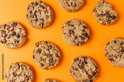 Chocolate chip cookie pattern on orange background, top view 