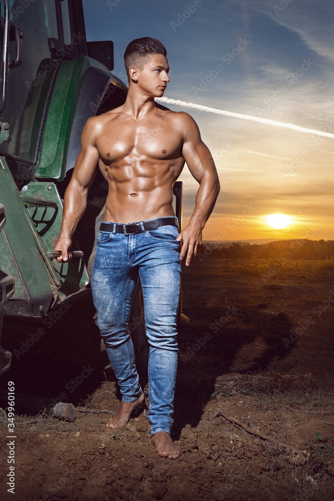 Muscular young sexy guy posing with a naked torso near the tractor in blue  jeans at sunset outdoors. Sexy young man with athletic body posing at  sunset. Stock Photo | Adobe Stock